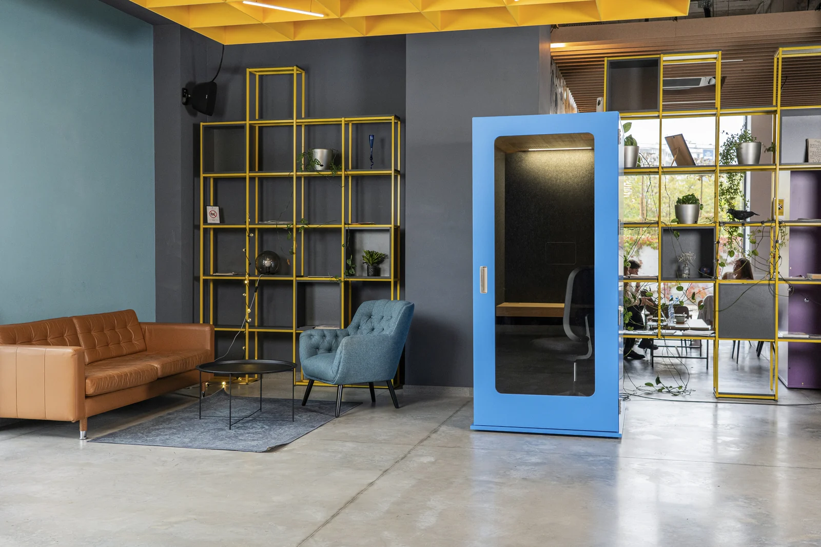 Blue MEAVO Workstation beside lounge seating and yellow shelving